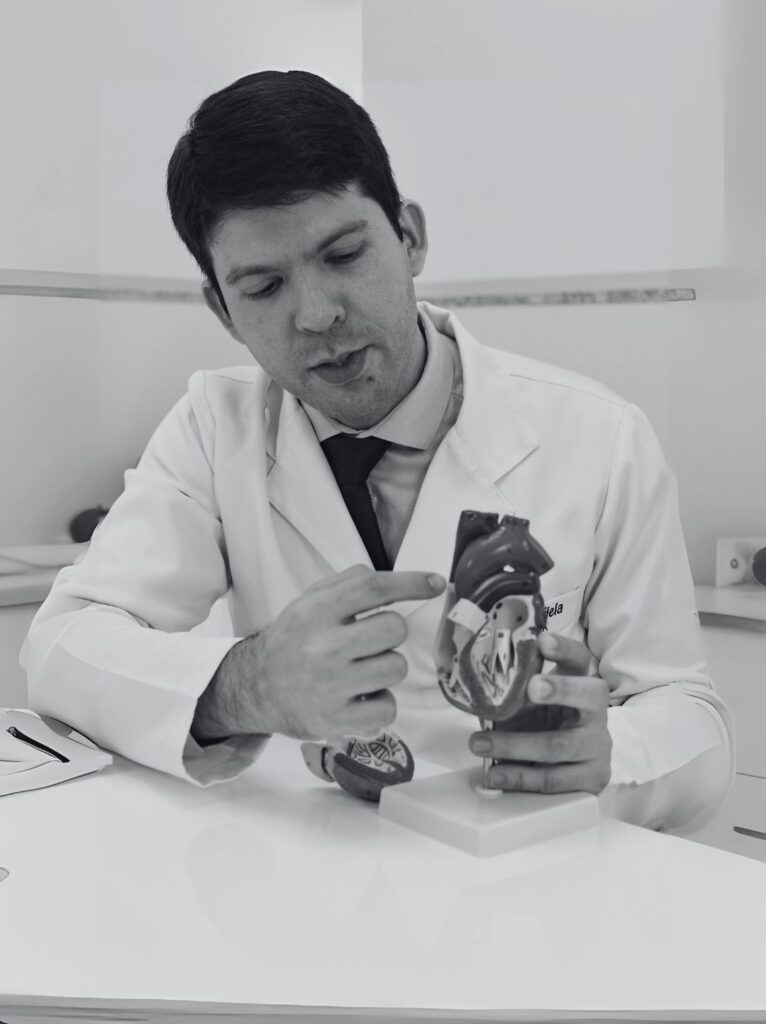 Foto do Dr. Murilo Vilela, cardiologista especializado em insuficiência cardíaca e transplante, sorrindo na fachada da Clínica Pulsarti